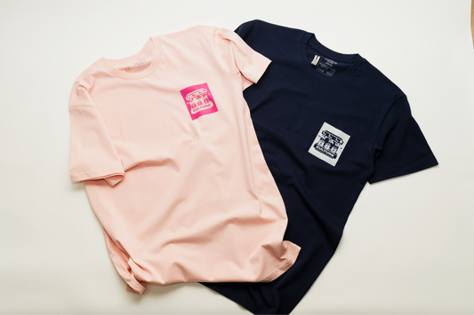 Two t-shirts, one pink and one navy, with small logos on a light background